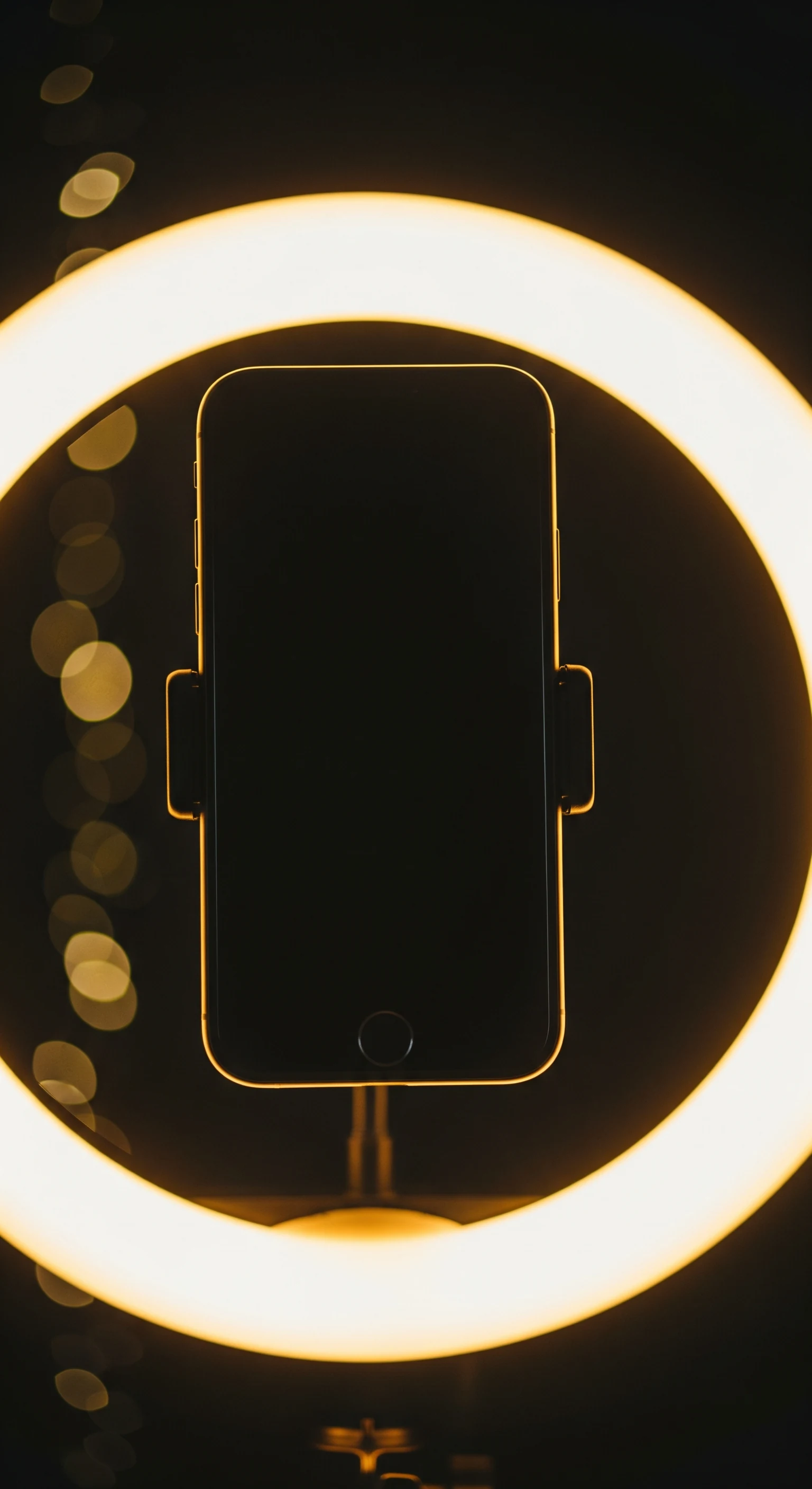ゴールドのリングライトに照らされたスマートフォンのライブ配信セットアップ